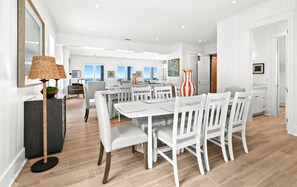 A spacious dining area with white furniture, a large window with a view, and a modern design.