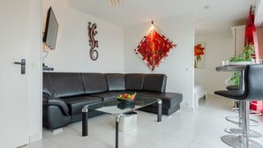 Ein modernes Wohnzimmer mit einer schwarzen Ledersofa, einem Glastisch und einem roten dekorativen Element an der Wand.