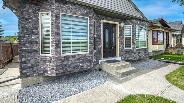 A modern two-story house with a stone facade, large windows, and a front porch.