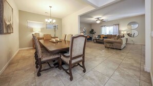 A spacious living area with a dining table and chairs, a sofa, and a ceiling fan. - Amazing 4 Bedroom 3 Bathroom Complete House (Tucson)