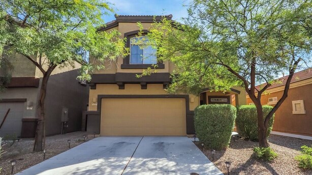 A two-story house with a garage, surrounded by trees and shrubs. - Amazing 4 Bedroom 3 Bathroom Complete House (Tucson)