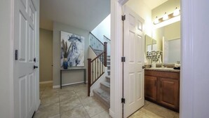 A hallway with a staircase leading to a bathroom. - Amazing 4 Bedroom 3 Bathroom Complete House (Tucson)