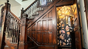 A wooden staircase with intricate balusters and a door with a patterned wallpaper design. - Historic-7BR/4.5BA-Walk to DC Sights + Parking (Washington)