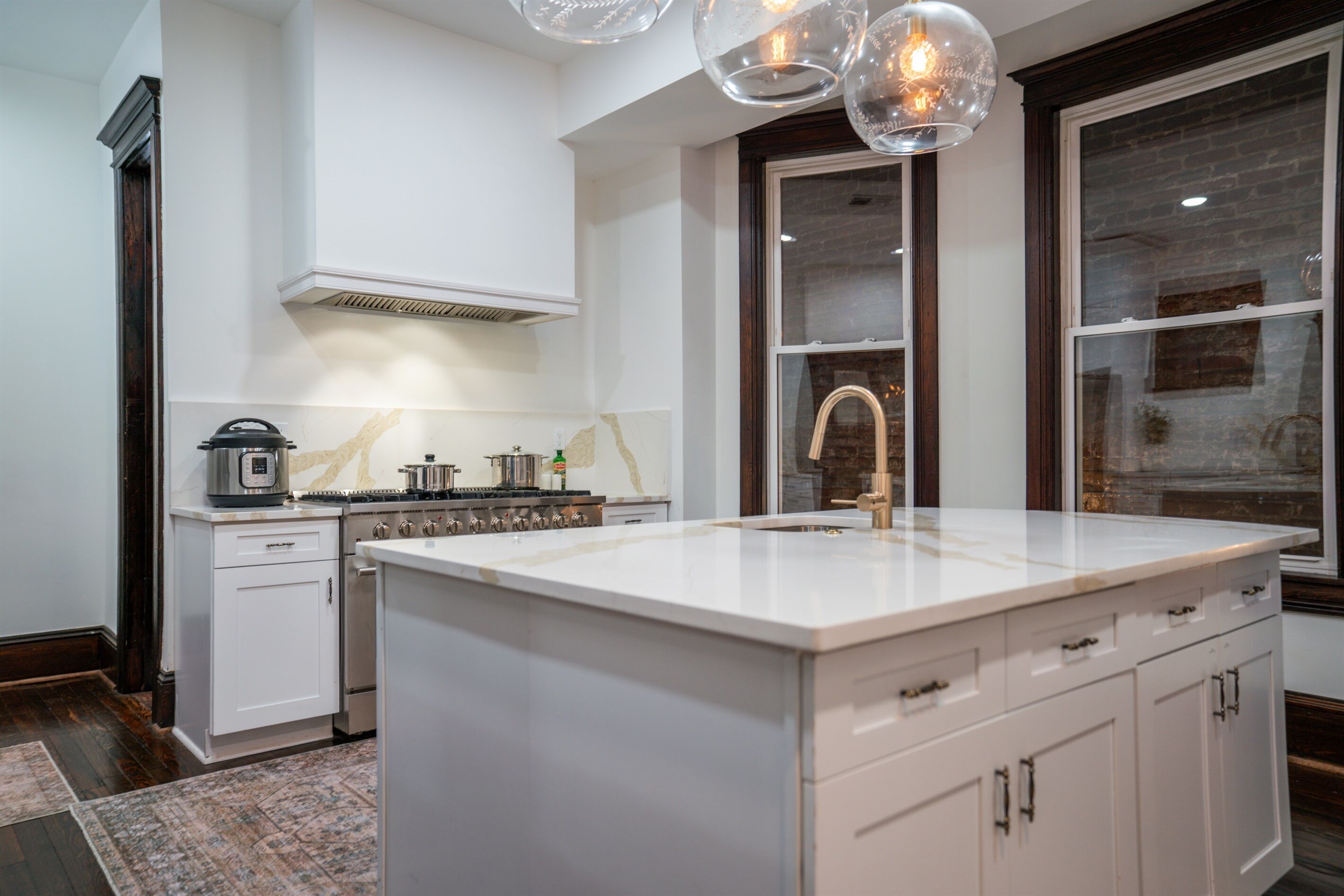 Een moderne keuken met witte kasten, een groot eiland en een inbouwoven.