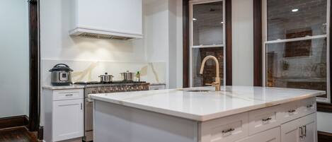 Een moderne keuken met witte kasten, een groot eiland en een inbouwoven.
