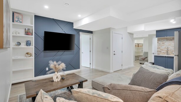 A modern living room with a flat-screen TV, a wooden coffee table, and a sofa.