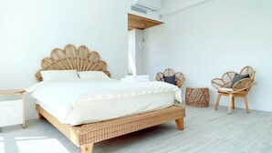 A modern bedroom with a large bed, wicker furniture, and a ceiling-mounted air conditioner. - guantau (Puli)