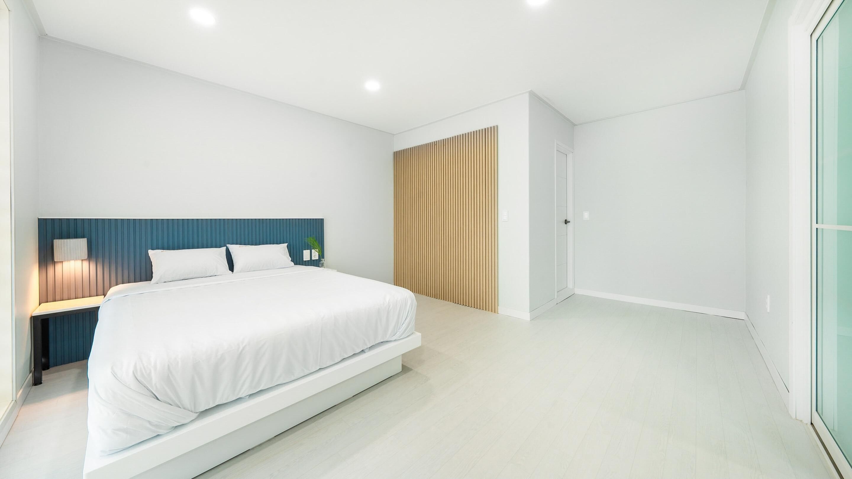 Une chambre à coucher moderne avec un grand lit, une table de chevet avec une lampe et un mur recouvert de panneaux en bois.
