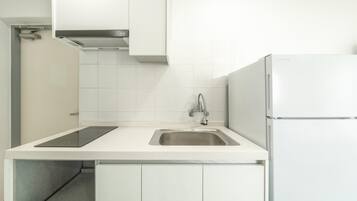 Una cocina moderna con un lavamanos de acero inoxidable, estufa integrada y refrigerador blanco.