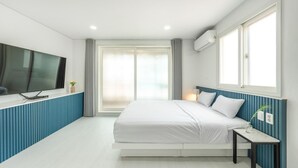 A modern bedroom with a bed, a TV mounted on the wall, and a window with curtains. - Taean Yeonpo Haibada Pension (Taean)