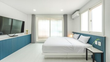 Un dormitorio moderno con una cama, un televisor montado en la pared y una ventana con cortinas.