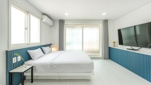 A modern hotel room with a bed, a TV, and a window with curtains. - Taean Yeonpo Haibada Pension (Taean)