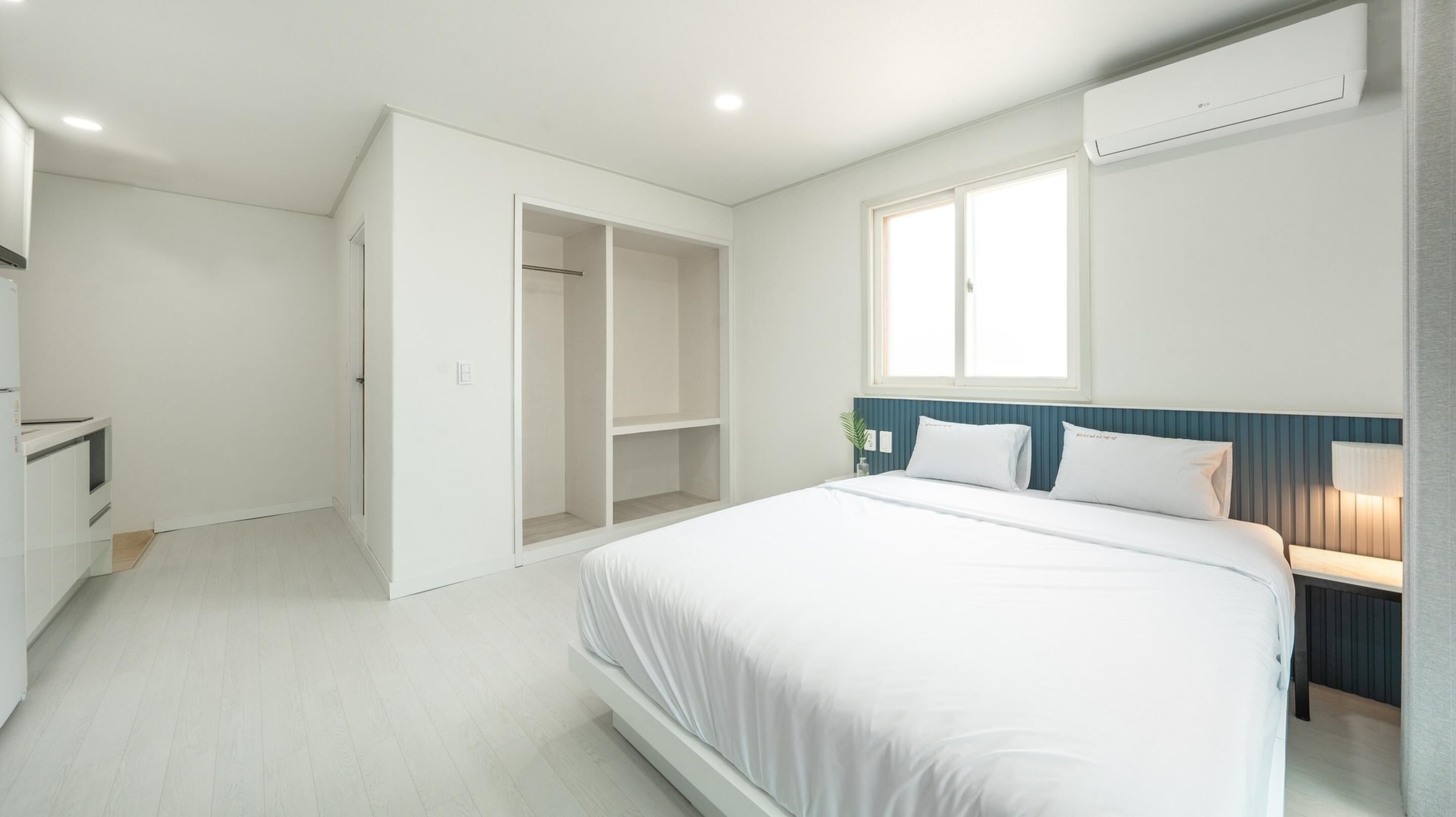Un dormitorio moderno con una cama grande, un armario y un estante empotrado.