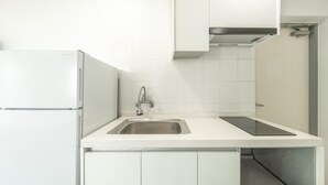 A compact kitchen with white cabinetry, a stainless steel sink, and a built-in range hood. - Taean Yeonpo Haibada Pension (Taean)