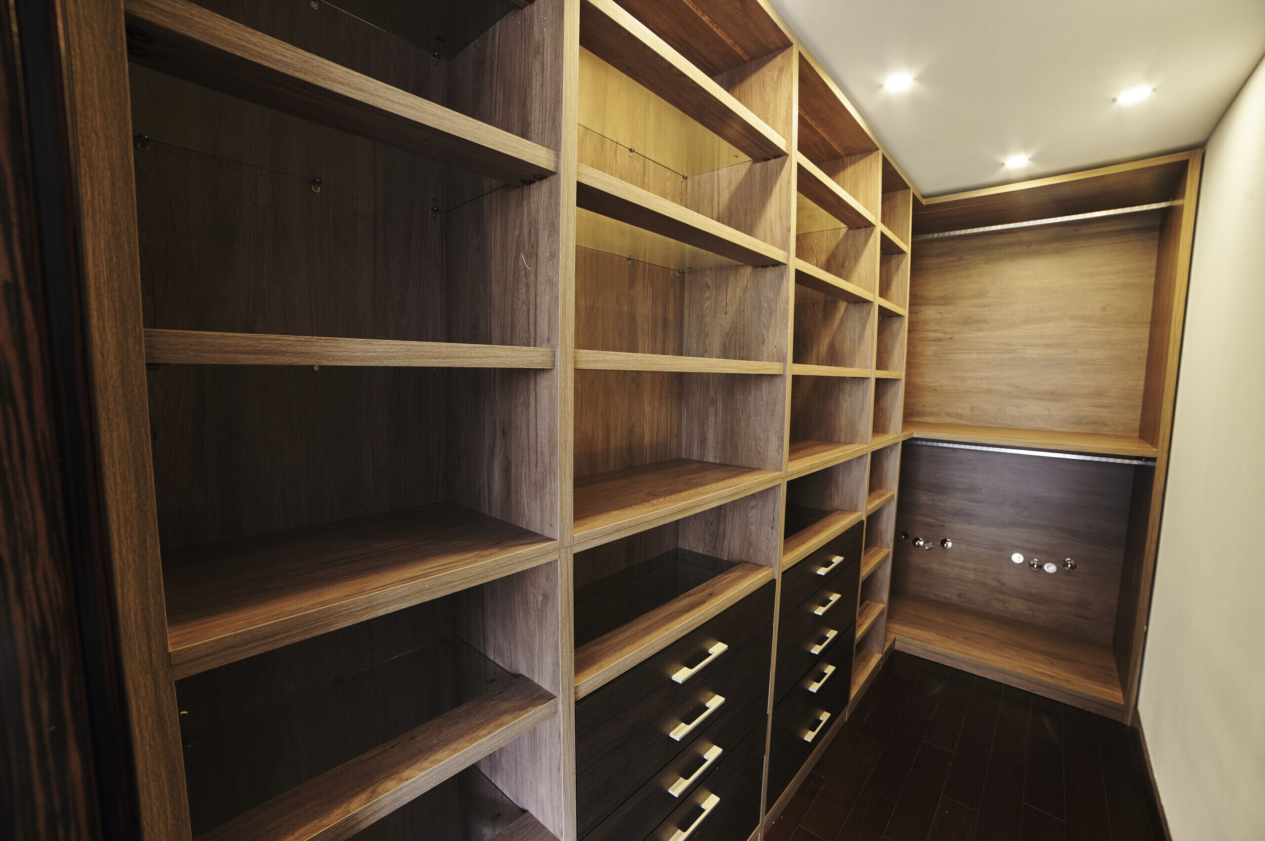 A walk-in closet with wooden shelving and drawers.