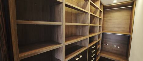 A walk-in closet with wooden shelving and drawers.