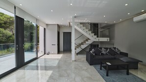 A modern living room with a dark sofa, a coffee table, and a staircase leading to an upper level. - WELCS VILLA MODERNA 097 EMP con piscina (Llança)