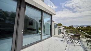 A modern building with large glass windows and a balcony with outdoor furniture. - WELCS VILLA MODERNA 097 EMP con piscina (Llança)