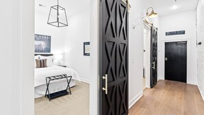 Una habitación de hotel moderna con una cama, una puerta negra y un letrero que dice 'BOUR-BON'.