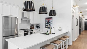 Una cocina moderna con armarios blancos, electrodomésticos de acero inoxidable y una isla grande con taburetes de bar.