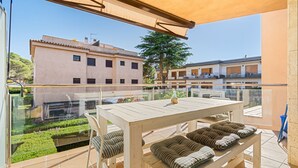 Un balcon avec une table et des chaises, une balustrade en verre et une vue sur les bâtiments voisins.