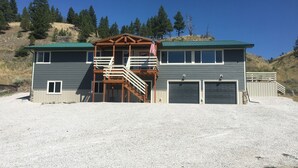 Ein zweigeschossiges Haus mit einer Holzterrasse, einer Veranda und einer Garage.