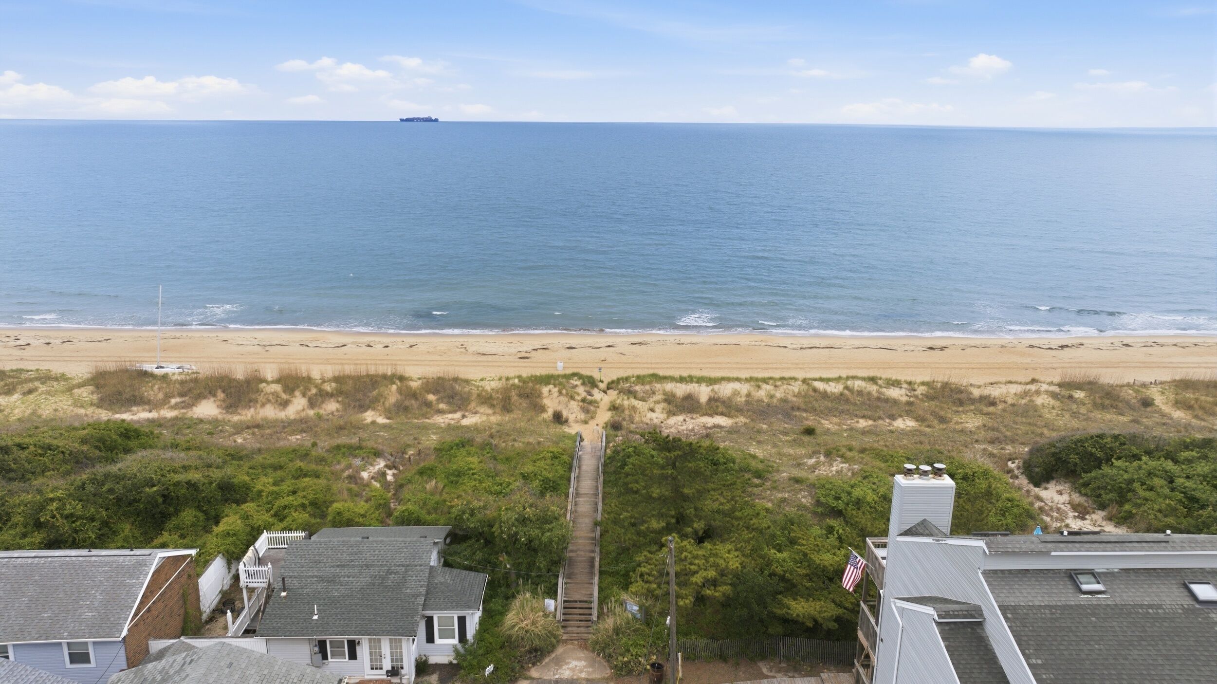 A coastal view with a beach, ocean, and residential buildings.