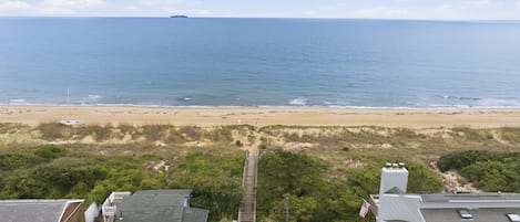 A coastal view with a beach, ocean, and residential buildings.