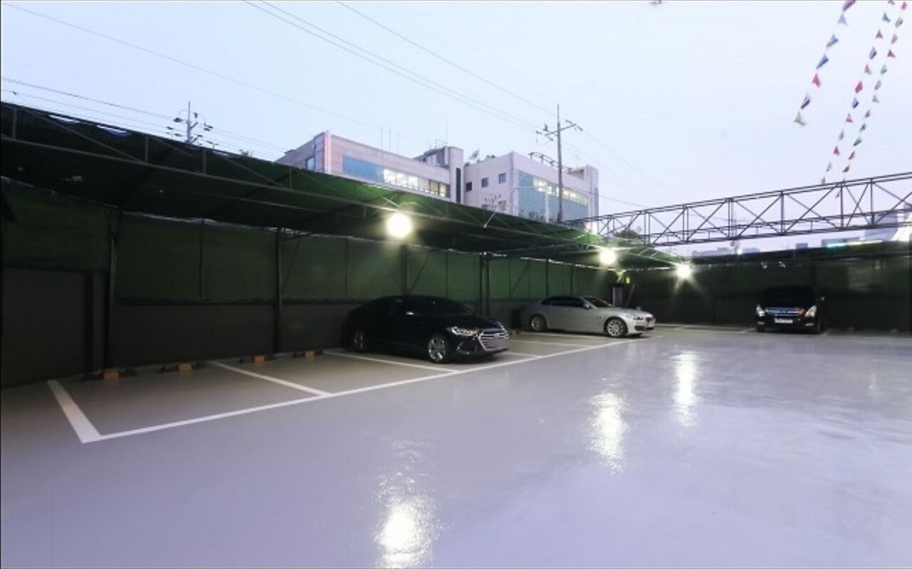 Un parking avec plusieurs voitures garées, un mur végétal et un bâtiment en arrière-plan.