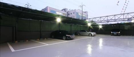 Un parking avec plusieurs voitures garées, un mur végétal et un bâtiment en arrière-plan.