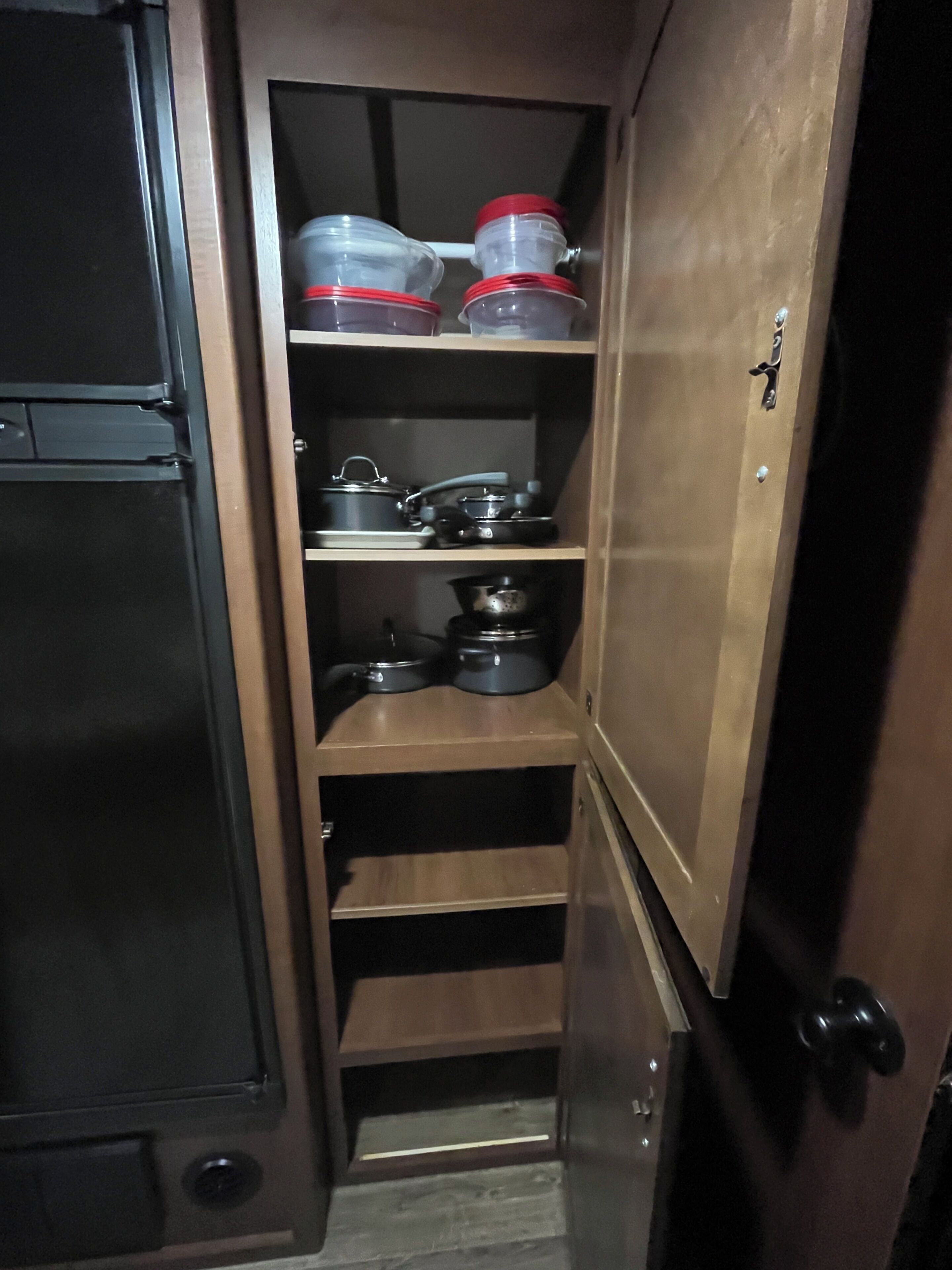 Eine Küche mit Holzausstattung, einem Kühlschrank und Regalen voller Küchenutensilien.