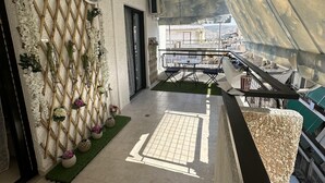 En korridor med utsikt över en stadsbild, en vägg av träribbor dekorerad med blommor och ett klinkergolv.
