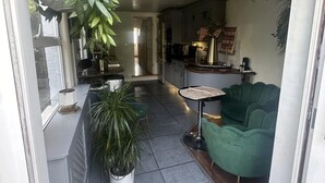 Una cocina moderna con zona de comedor, que incluye un sofá verde, una mesita y plantas en macetas.