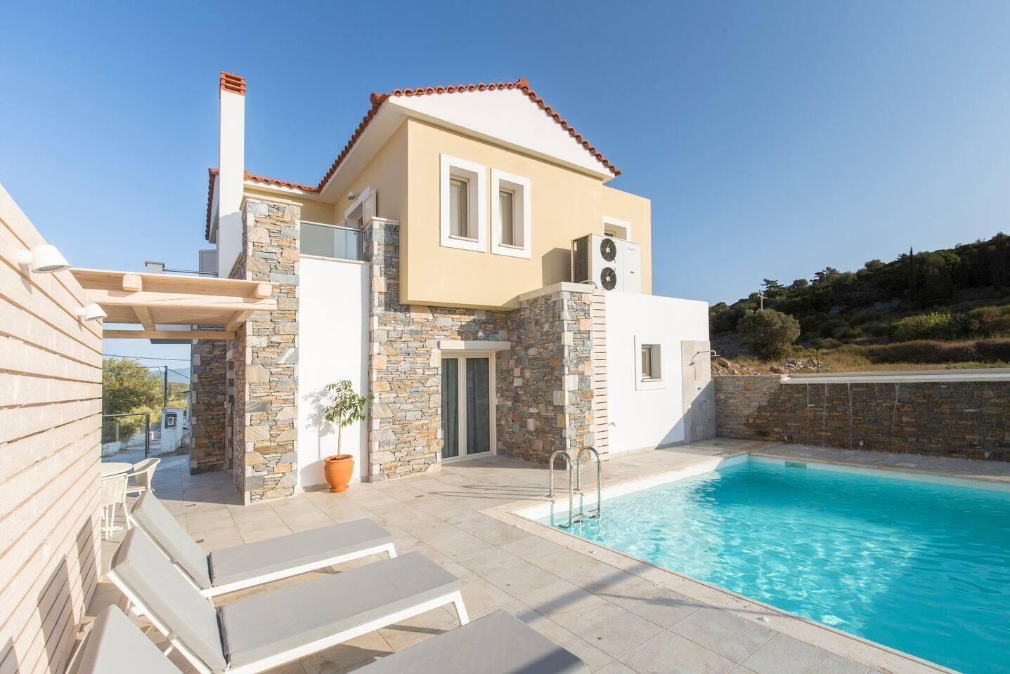 A modern villa with a stone facade, a swimming pool, and outdoor seating.