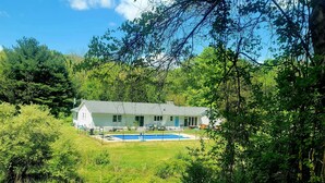 A house with a swimming pool surrounded by lush greenery. - Secluded Mountaintop Retreat – Rustic Luxury & Panoramic Views at Freedom Farm (New Milford)