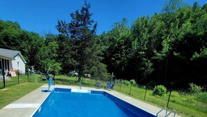 A rectangular swimming pool with a blue interior, surrounded by a concrete deck. - Secluded Mountaintop Retreat – Rustic Luxury & Panoramic Views at Freedom Farm (New Milford)