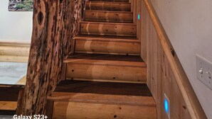 A wooden staircase with a chandelier, wooden walls, and a small window. - Gilbert Creek Lodge, your Home Sweet Home in the Uinta's! (Mountain View)