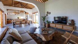 A spacious living area with a modern sofa, a wooden coffee table, and a television. - Villa Rumiano II (Ubud)