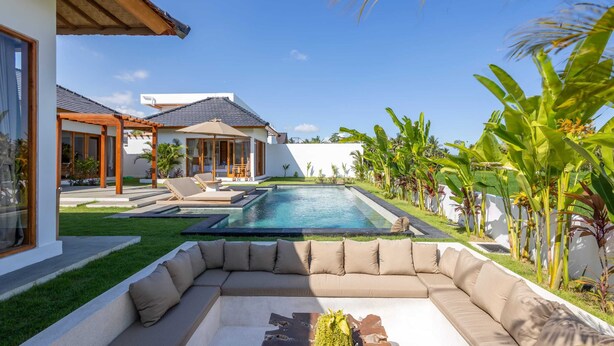 A modern house with a swimming pool, a large outdoor seating area, and lush tropical plants. - Villa Rumiano II (Ubud)