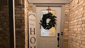 A front door with a wreath, a welcome sign, and a doormat.