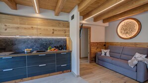 A modern kitchen with dark cabinets, a wooden ceiling, and a round wall decoration. - Belfiore, Livigno, Italy (Livigno)