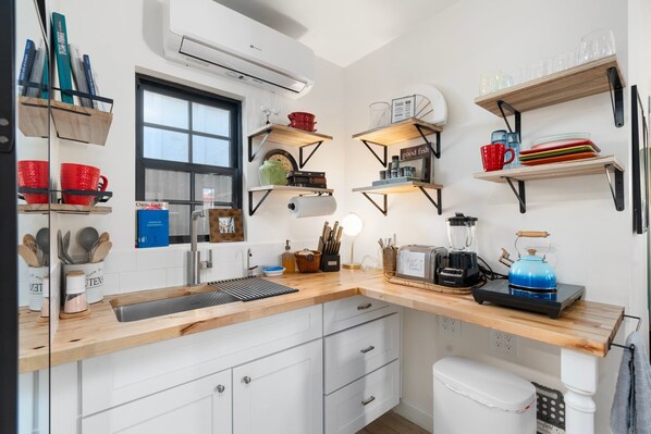 A modern kitchen with wooden countertops, built-in shelves, and various kitchen appliances.