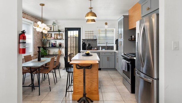 Una cocina moderna con una isla central, electrodomésticos de acero inoxidable e iluminación colgante.