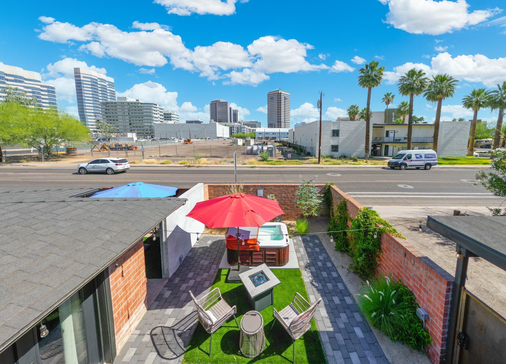 A rooftop patio with a hot tub, outdoor seating, and a view of the city skyline.