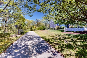 Stroll through a serene residential street lined with mature trees and a charming white picket fence.