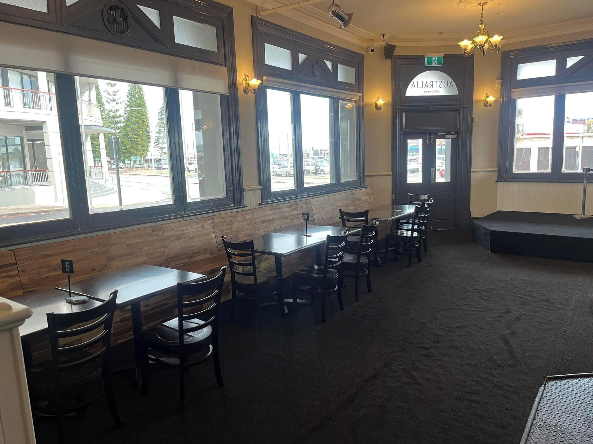 A restaurant interior with wooden paneling, large windows, and a stage area.