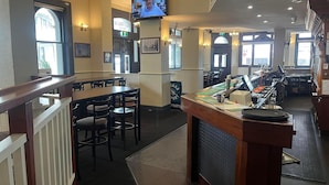 A restaurant with a bar area, tables, chairs, and a television screen. - Australia Hotel Fremantle (Fremantle)