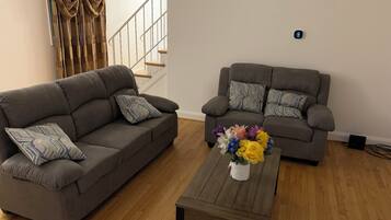 A living room with two grey sofas, a wooden coffee table, and a floral centerpiece.