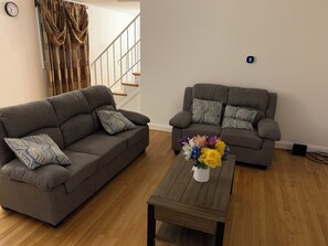 A living room with two grey sofas, a wooden coffee table, and a floral centerpiece. - Townhouse near Towson (Parkville)