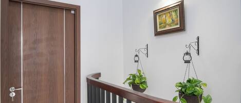 Een trap met een houten leuning en zwarte spijbels, leidend naar een kamer met witte muren en een houten deur.